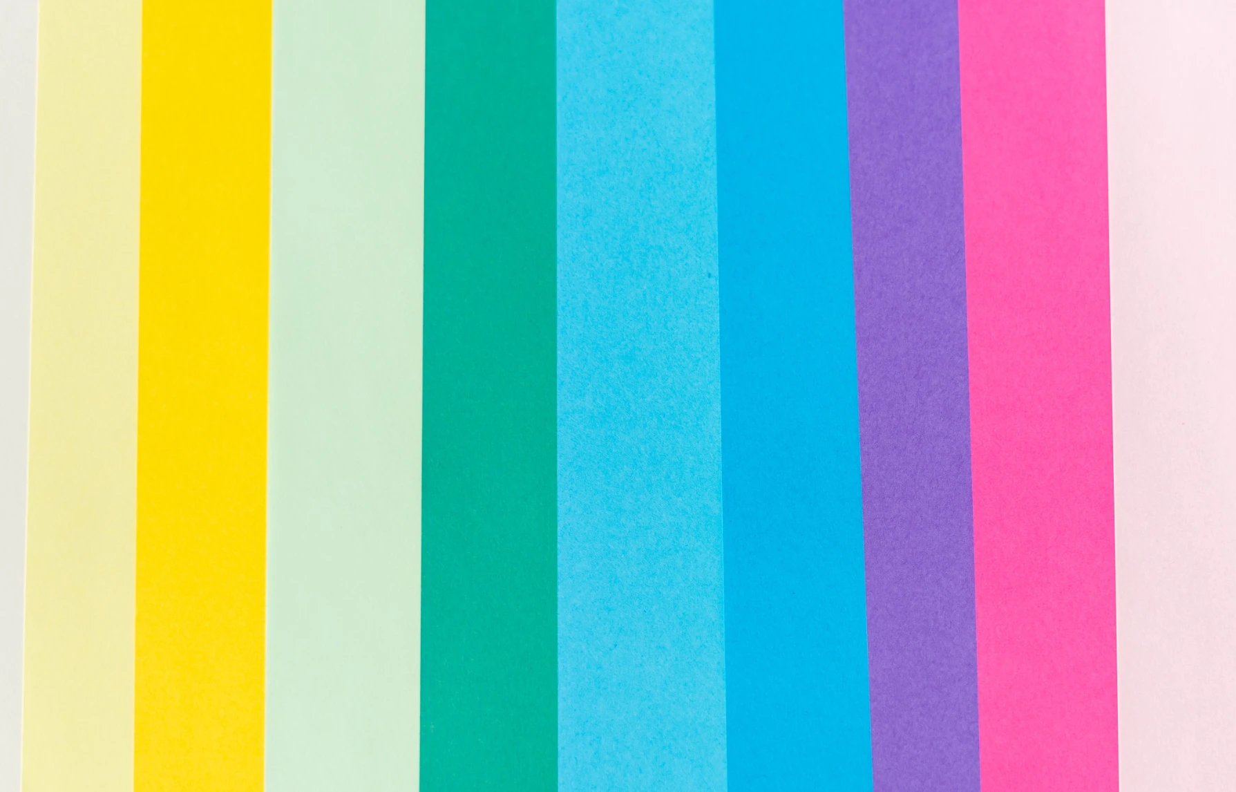 Vertical stripes of pastel and bright coloured paper in yellow, mint, green, blue, purple and pink